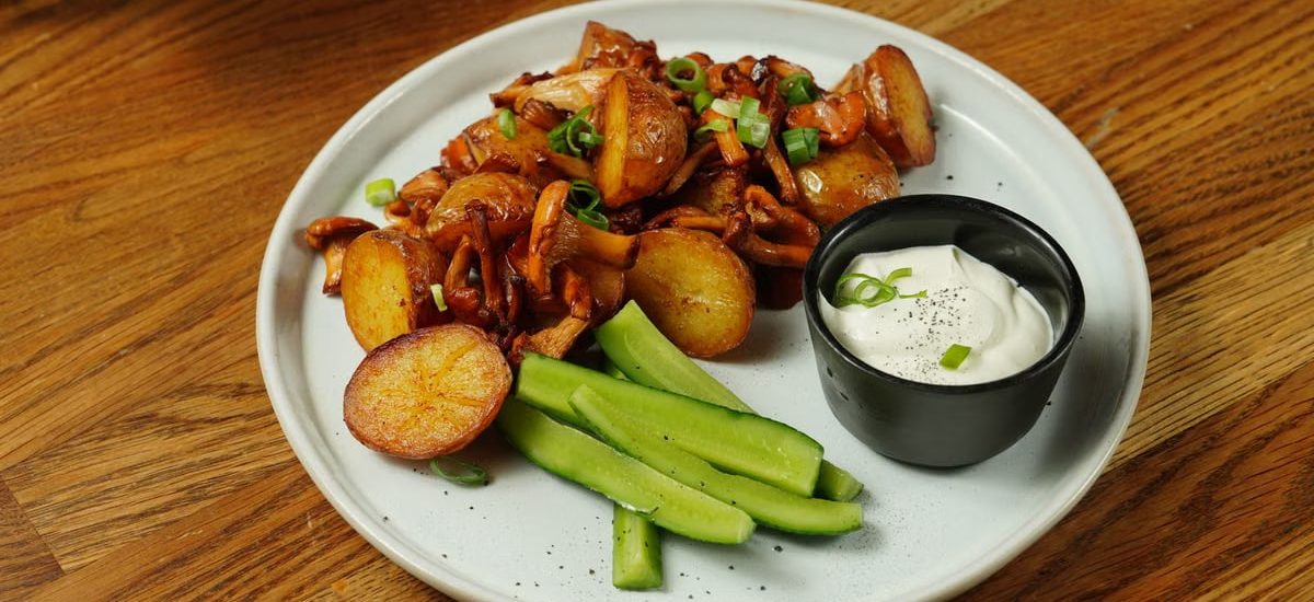 A delectable plate of roast potatoes served with chanterelle mushrooms and fresh cucumbers.