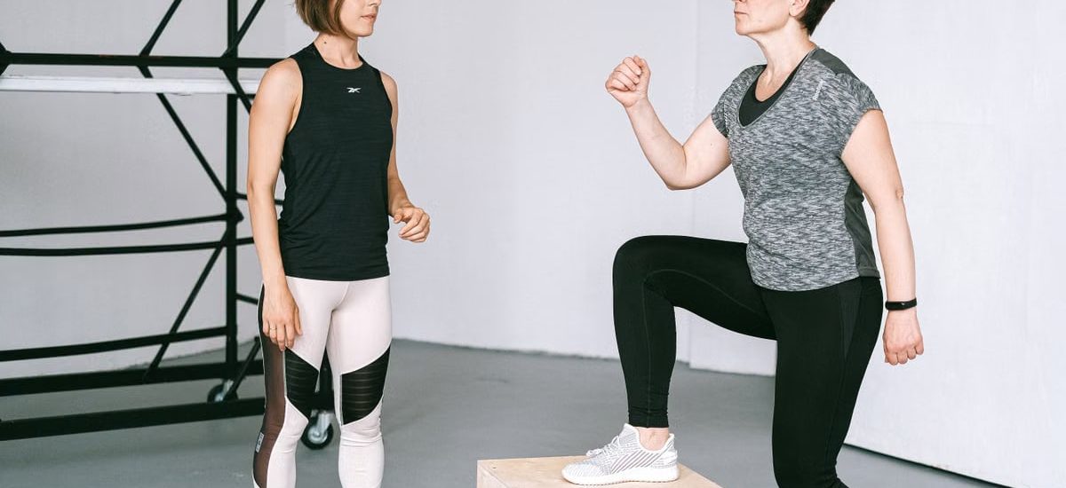 Fitness coach guides a woman in workout indoors. Focus on exercise and healthy lifestyle.