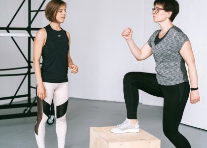 Fitness coach guides a woman in workout indoors. Focus on exercise and healthy lifestyle.